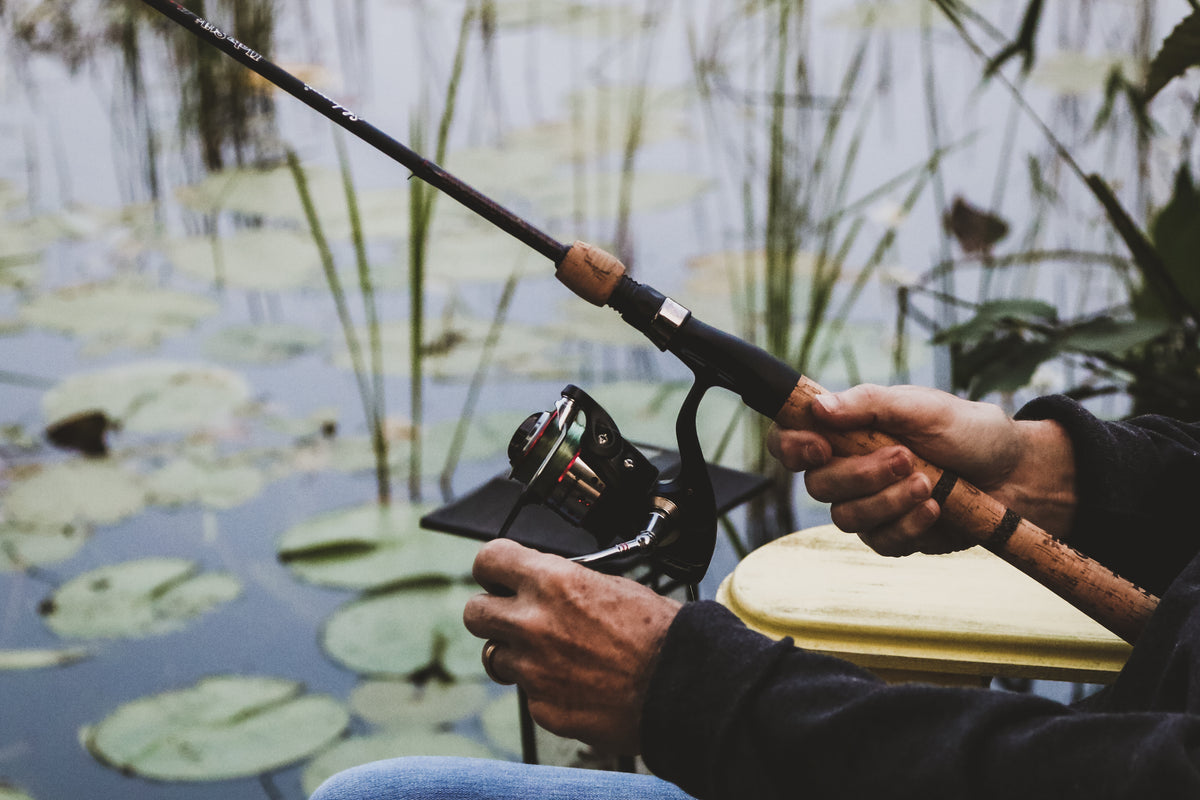 Angler holding a cork-handled fishing rod beside the water